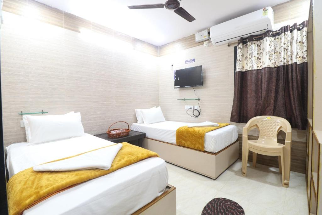 a hotel room with two beds and a tv at HOTEL VALLABHA RESiDENCY in Rājahmundry