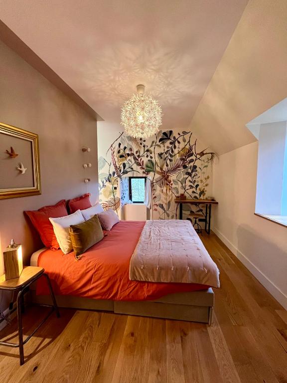 une chambre avec un grand lit et un lustre dans l'établissement Domaine de la Bigottière, Chambres d'hôtes, à Montigné-le-Brillant