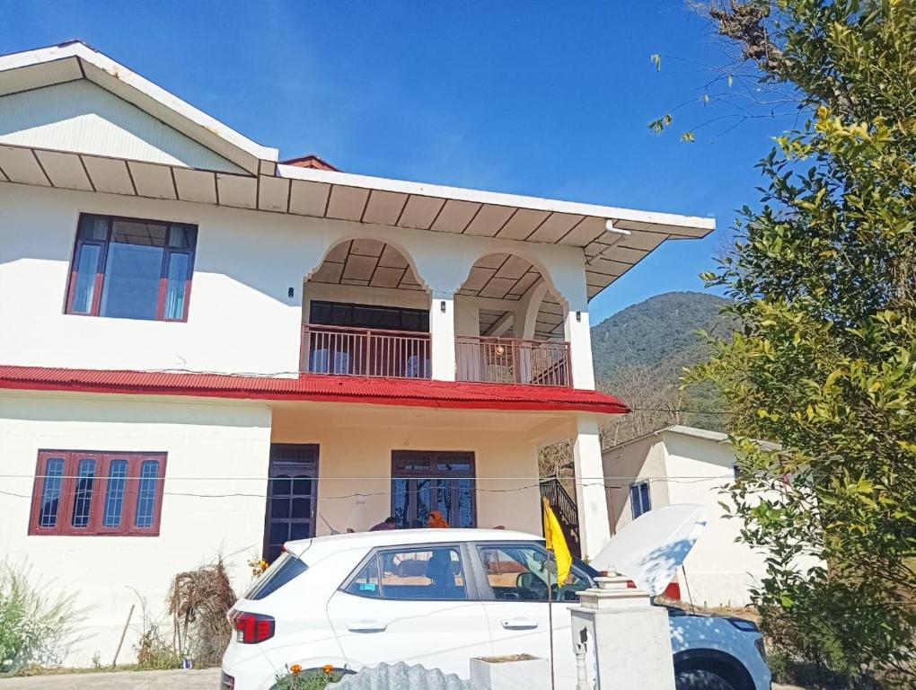 Un coche blanco aparcado delante de una casa en Isha Villa, en Pālampur
