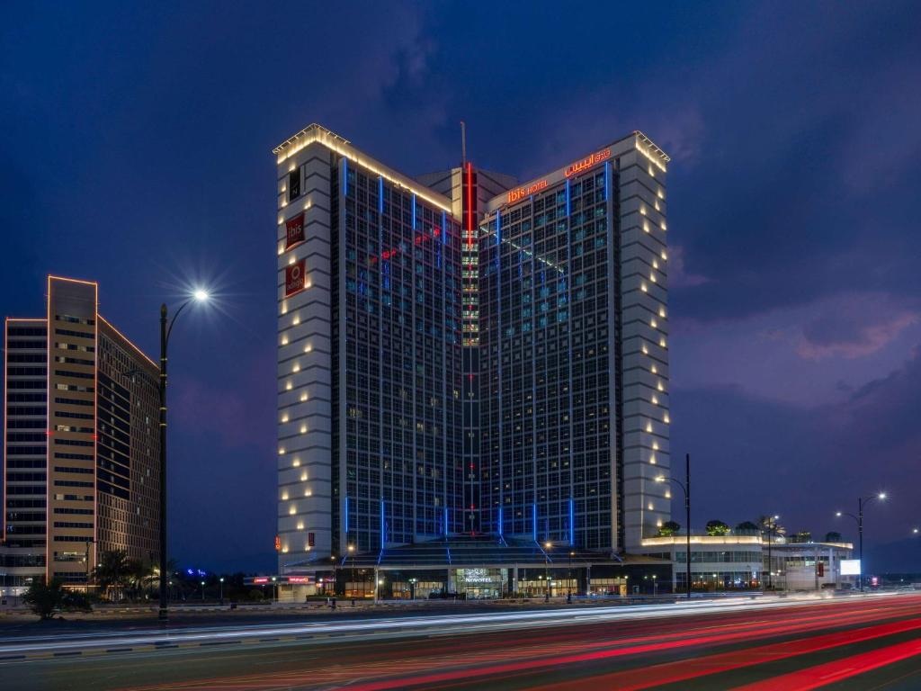 a tall building with lights on it at night at Novotel Fujairah in Fujairah