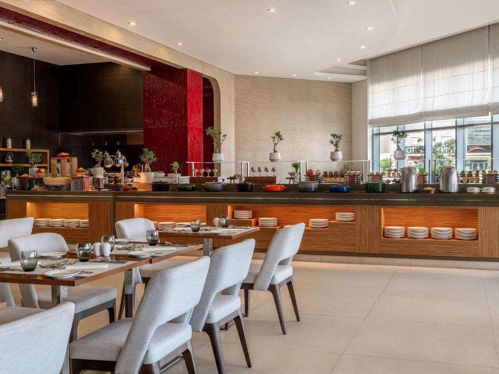 a restaurant with wooden tables and white chairs at Novotel Fujairah in Fujairah