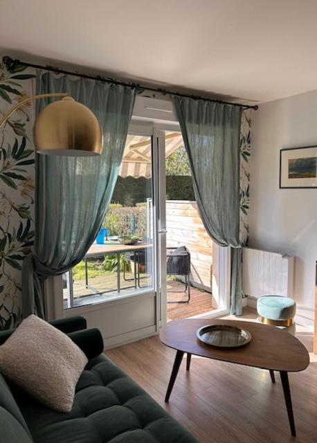 un salon avec un canapé et une table dans l'établissement Appartement coquet avec jardin proche de la mer, à Ouistreham