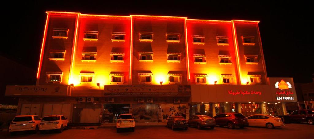 un edificio iluminado con coches estacionados frente a él en Manazel Al Hamra Apartment 2, en Buraidah