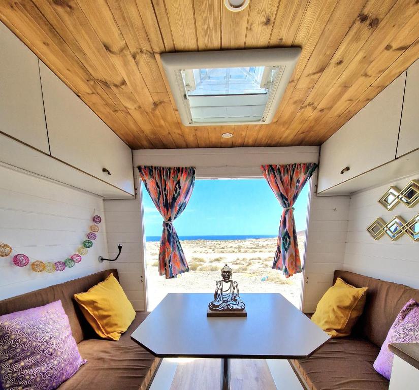 厄尔梅达诺Static Camper in front of the Sea的一个小房子,有桌子和窗户