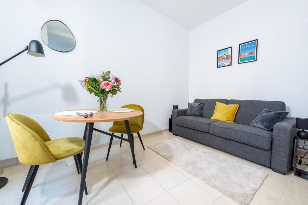 un salon avec un canapé et une table avec des fleurs dans l'établissement Iconic Central Flat, à Nice