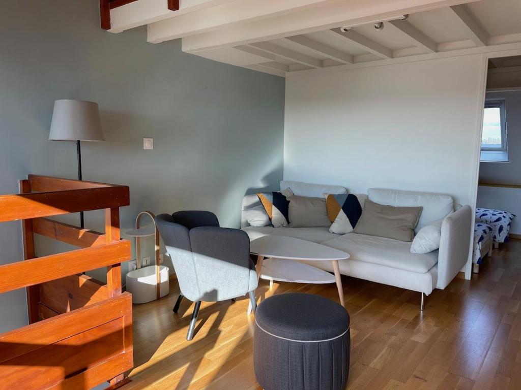 a living room with a couch and a table and chairs at Appartement Ô Nid Perché Vue mer in Agon Coutainville