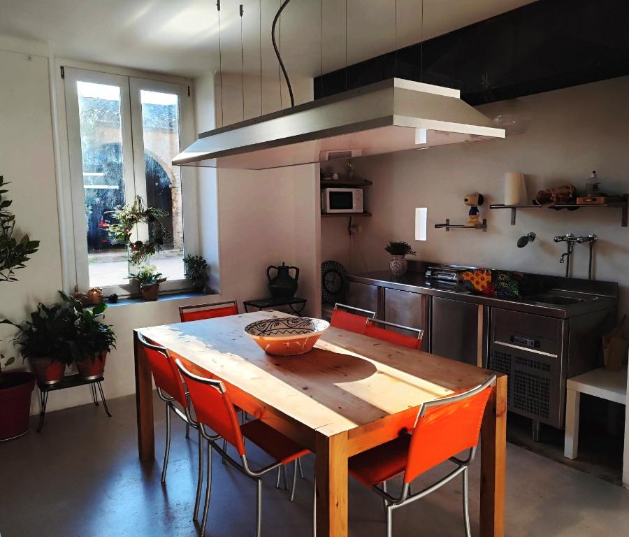 - une cuisine avec une table en bois et des chaises orange dans l'établissement Les Grands Cyprès - chambres d'hôtes, à Conques-sur-Orbiel