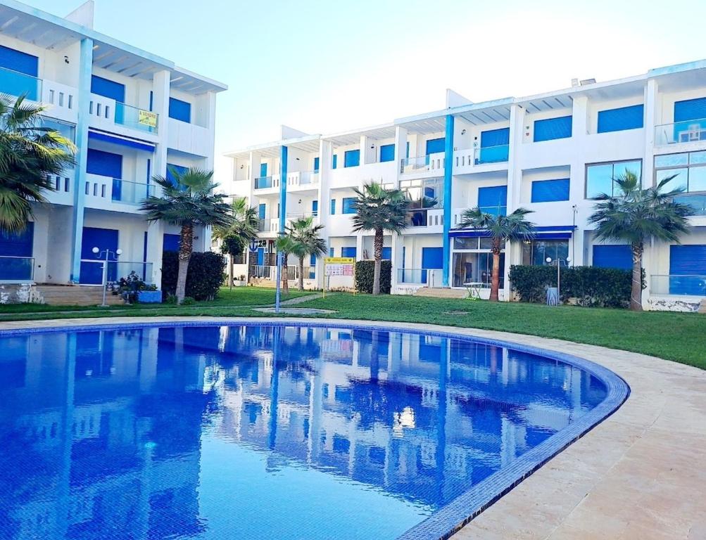 a swimming pool in front of a building at appartement à Mansouria avec piscine et accès a la mer Perla Andaloussia El Mansouria in Mansouria
