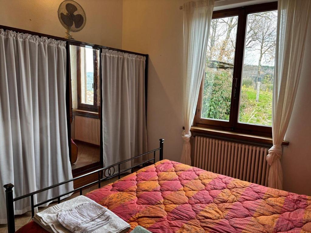 une chambre avec un lit et une grande fenêtre dans l'établissement Antica Fiera, à Caprese Michelangelo