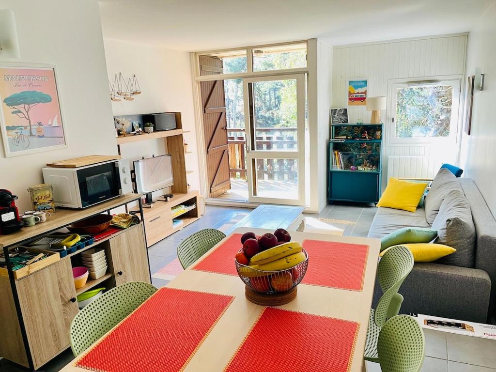 un salon avec une table avec un bol de fruits dessus dans l'établissement Apt T3 avec terrasse, sous les pins, au bord du lac et à 5 min de l'océan, à Carcans
