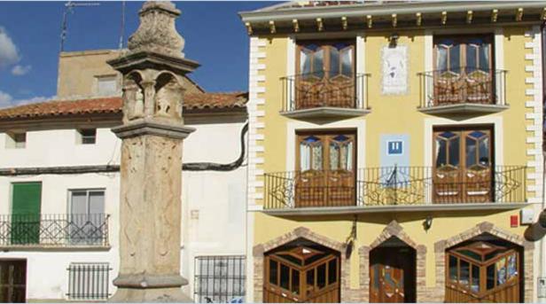 un edificio con una torre frente a un edificio en Hostal Las Grullas en Tornos