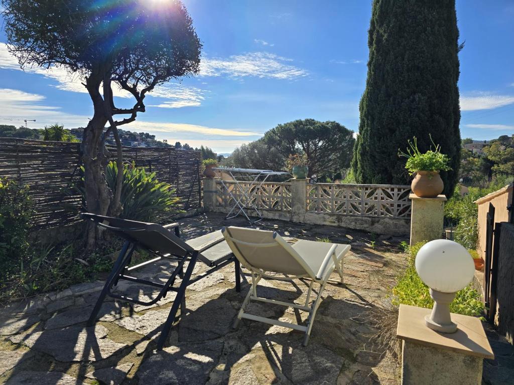 une terrasse avec 2 chaises, une table et un arbre dans l'établissement Les Hauts de Bormes Mazet, à Bormes-les-Mimosas