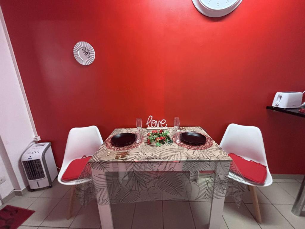 une table à manger avec des chaises et un mur rouge dans l'établissement Regal spa, à Calais