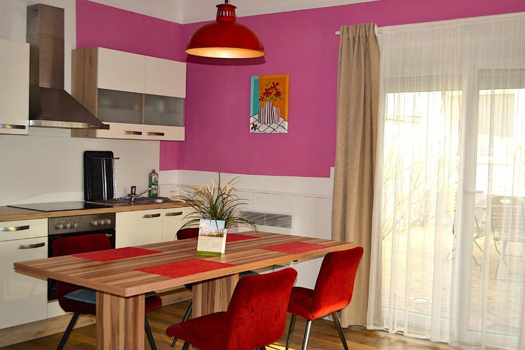 a kitchen with a wooden table and red chairs at Ferienwohnungen Halbturn in Halbturn