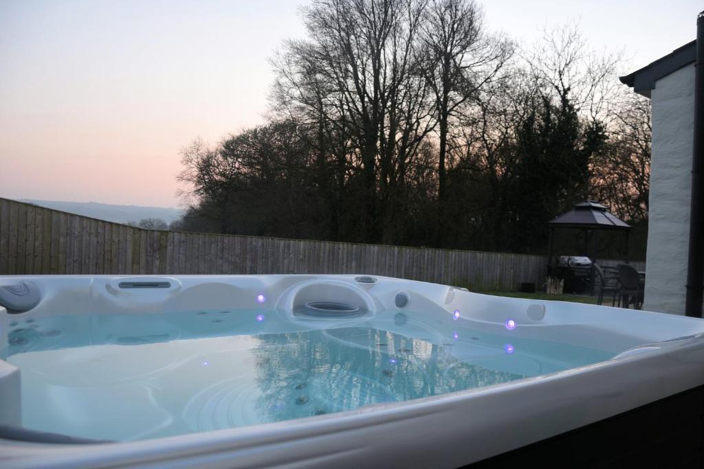 a jacuzzi tub in a backyard with a fence at Y Felin Cottage in Cardigan
