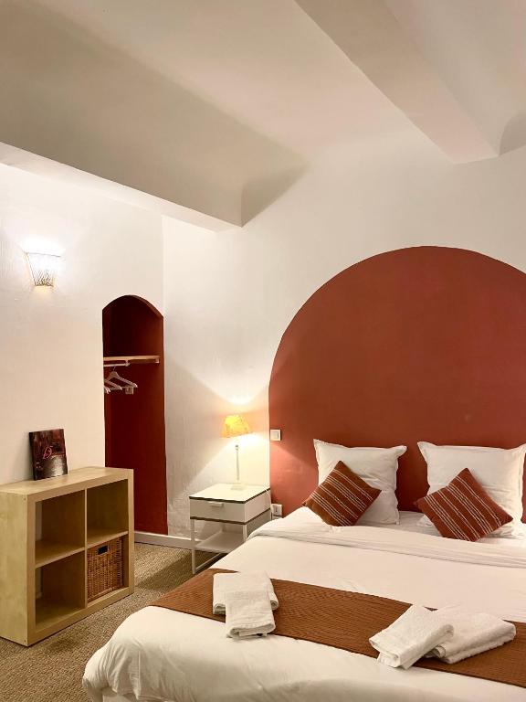 une chambre avec un grand lit avec une grande tête de lit dans l'établissement La Villageoise, à Aups