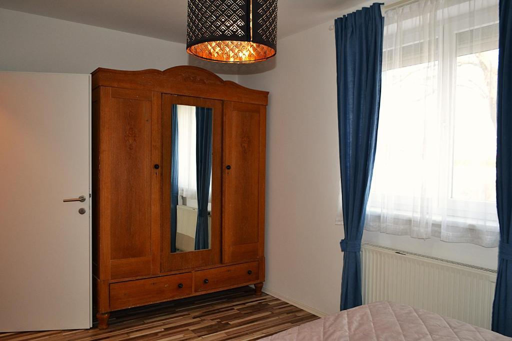 a bedroom with a wooden cabinet with a mirror at Ferienwohnungen Halbturn in Halbturn
