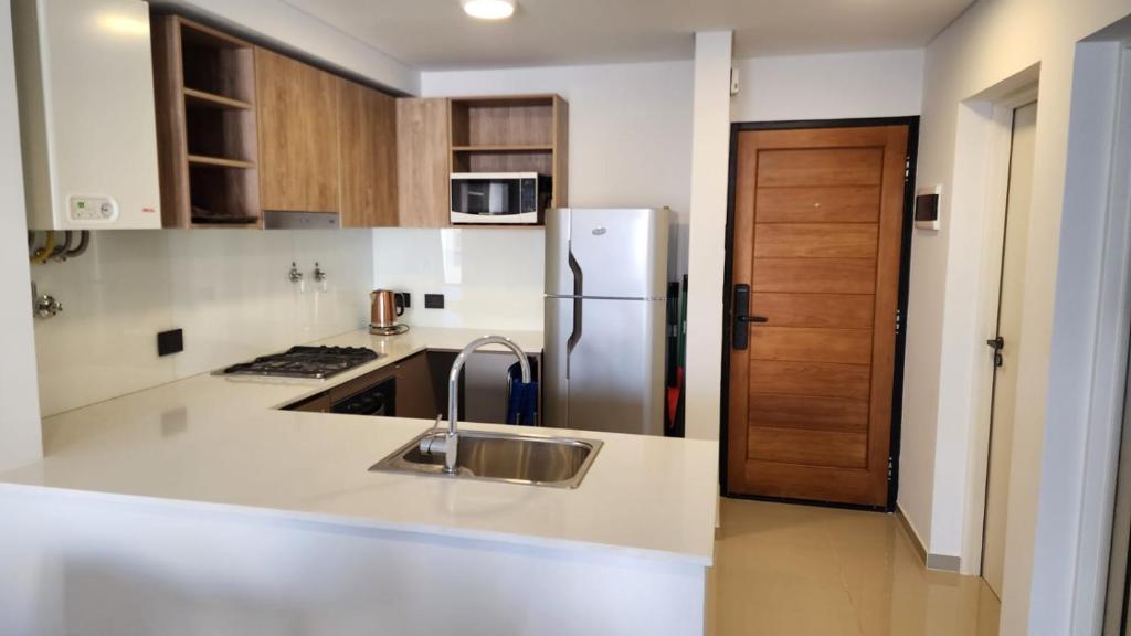 una cocina con fregadero y refrigerador en Caleta Design Puerto Madryn, en Puerto Madryn