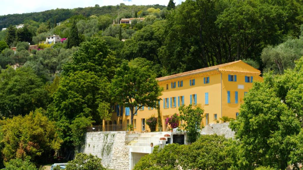 une maison jaune au milieu d'une forêt dans l'établissement Domaine de la Cascade Parfumée, à Grasse