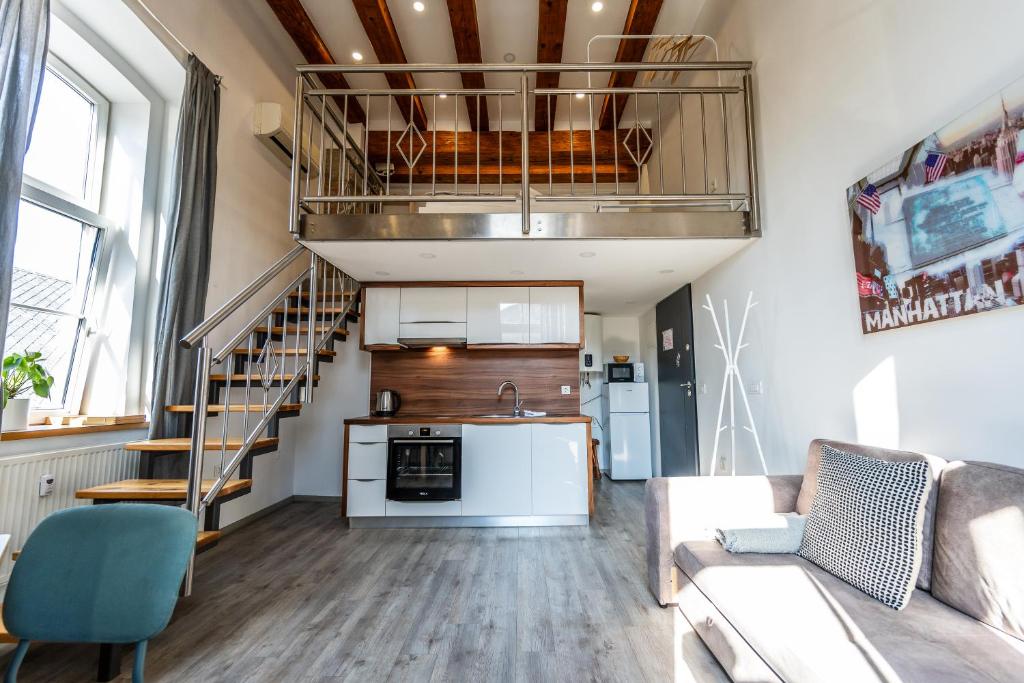 sala de estar con sofá, cocina y escalera en The Wonderful Loft, en Liubliana