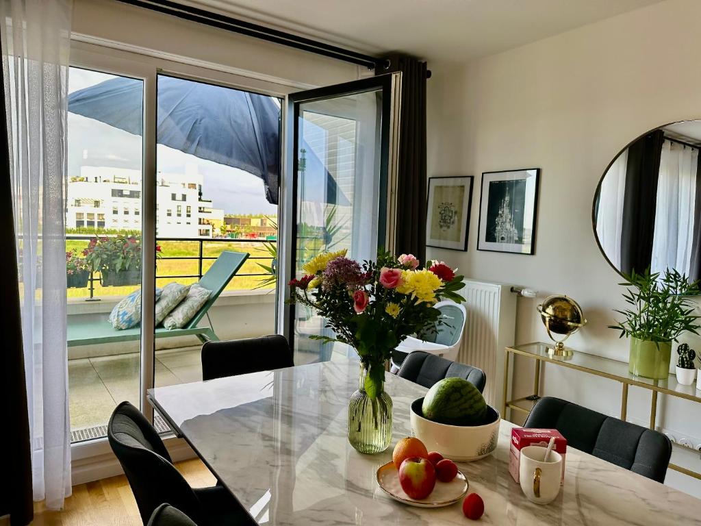 une salle à manger avec une table avec un vase de fleurs dans l'établissement Appt 6 personnes - Vue sur le Parc Disneyland-PARIS - Parking Privé, à Chessy