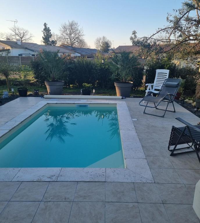 - une piscine dans une cour avec 2 chaises dans l'établissement Maison biganos bassin d arcachon, à Biganos