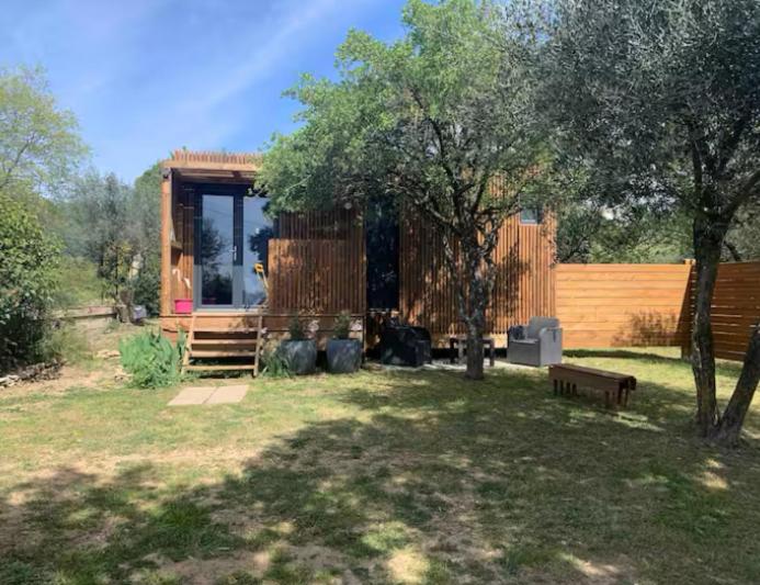 a log cabin with a bench in a yard at La chambre des oliviers in Aubais