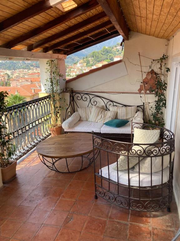 - une terrasse couverte avec un canapé et une table sur un balcon dans l'établissement Stunning 3BR Full Ocean View - Town Center Menton, à Menton