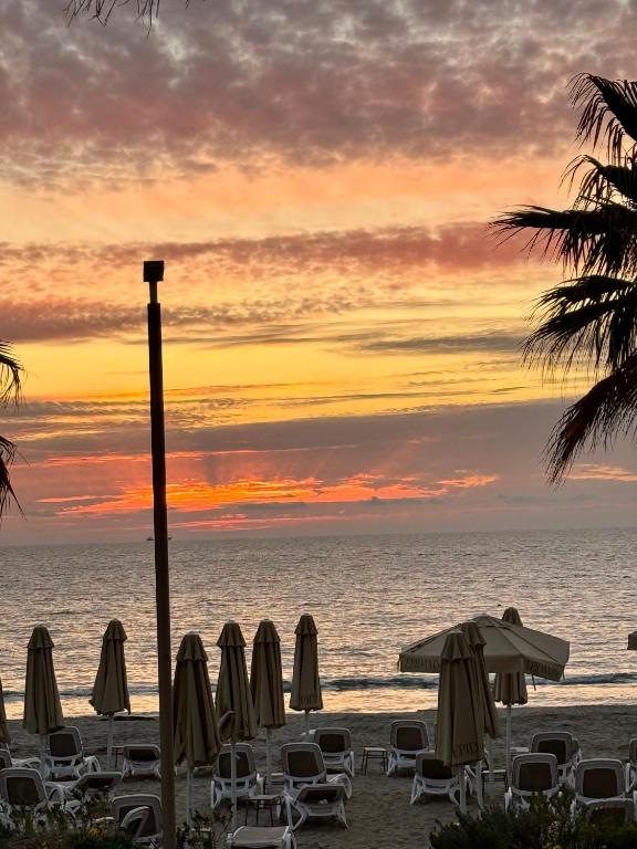 a group of chairs and umbrellas on the beach at sunset at Beach Apartments Durres in Durrës