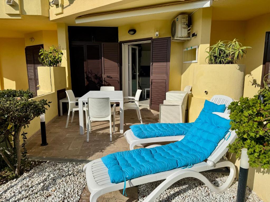 patio z krzesłami i stołem z niebieską poduszką w obiekcie Appartamenti delfini terza spiaggia w mieście Golfo Aranci