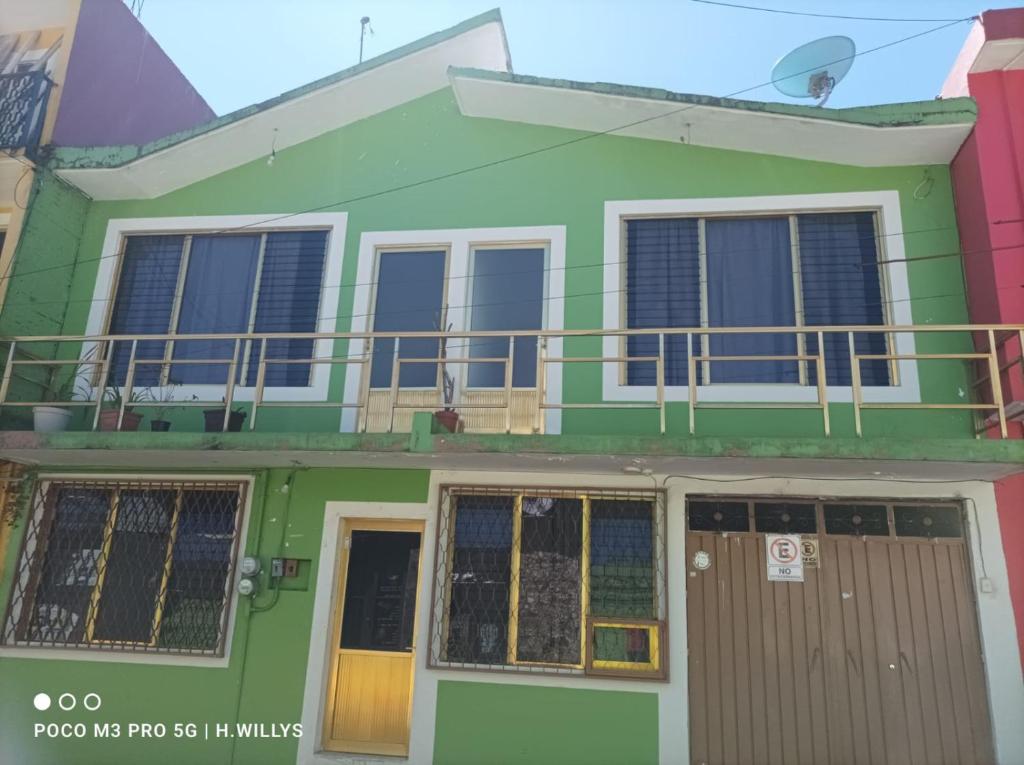 a green house with a balcony on top of it at Villa De Juarez Carmen in Xicotepec de Juárez