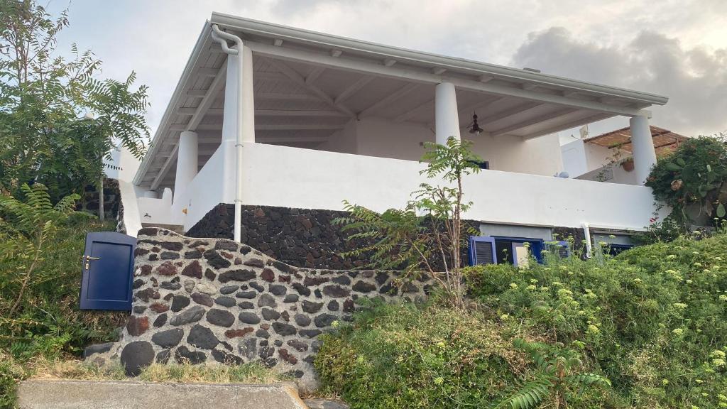 a white house with a stone wall in front of it at La casa del vecchio molo in Stromboli