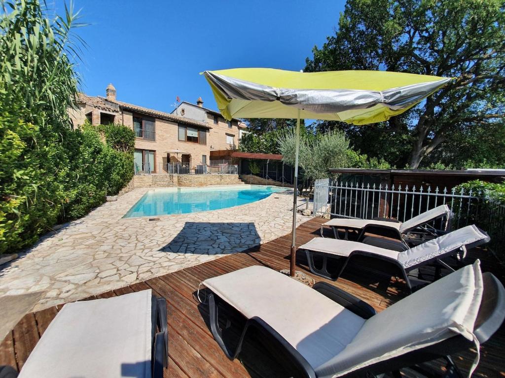 - un groupe de chaises et un parasol à côté de la piscine dans l'établissement Villa Martin with private pool for 5 people, à Montegranaro