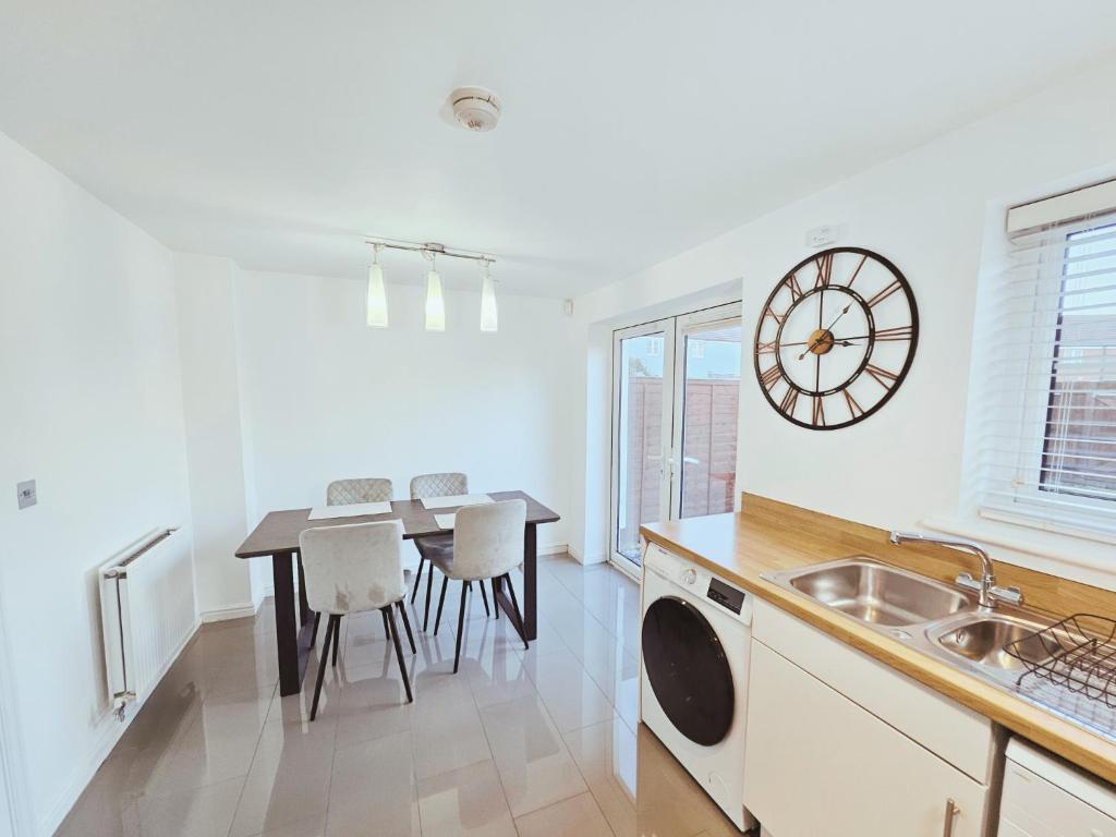 eine Küche mit einem Tisch und einer Uhr an der Wand in der Unterkunft Spacious 3 Bedroom HOUSE in Dartford,London Zone 8 in Dartford