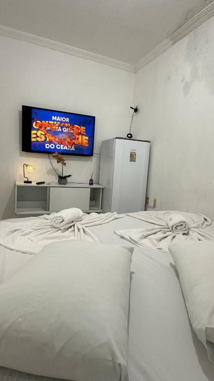 a room with two white beds and a tv on the wall at Pousada Iracema Centro in Fortaleza