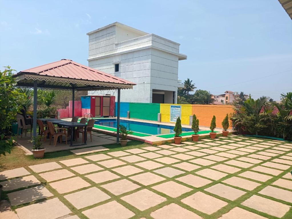 a patio with a table and a gazebo at Palm Villa and Cottage in Alibaug