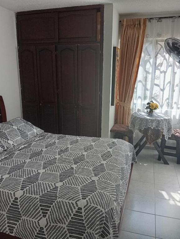 a bedroom with a bed and a table and a window at Habitación Conj parque San Agustín, Floridablanca in Floridablanca