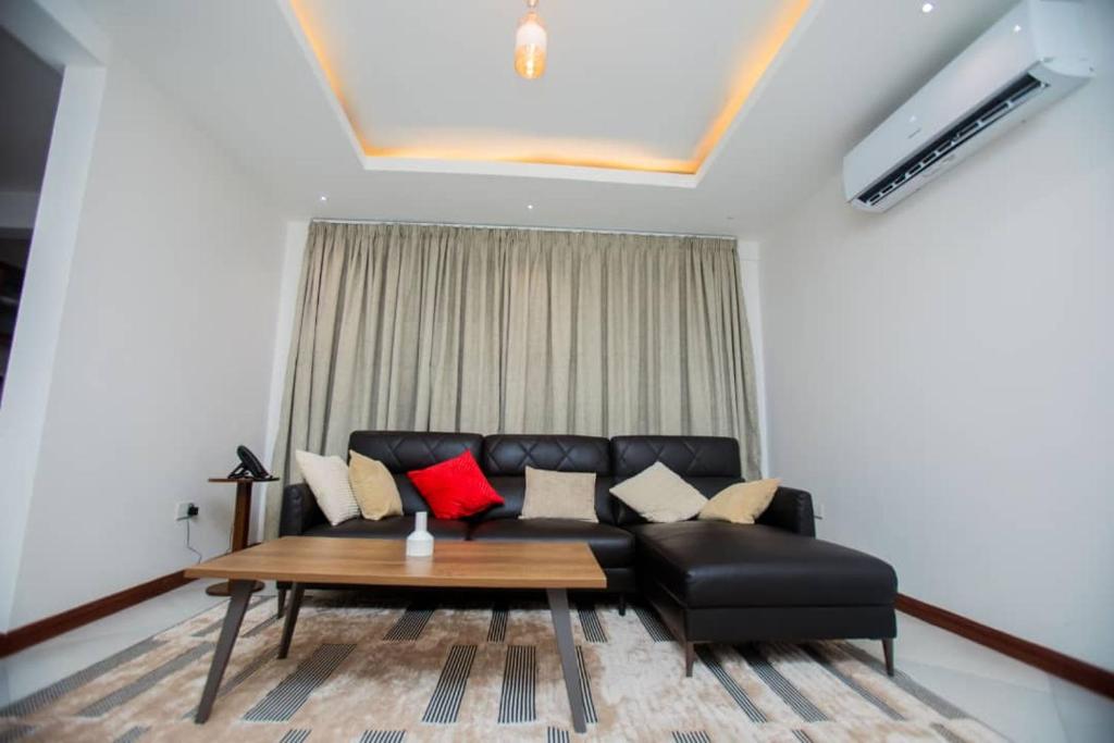 a living room with a black couch and a table at Comfort Retreat 2 in Dar es Salaam