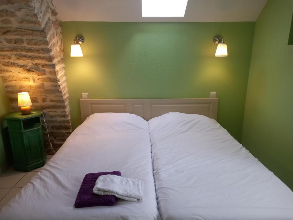 a bed with white sheets and a purple towel on it at Gîte La Grange in Saint-Laurent-dʼOlt