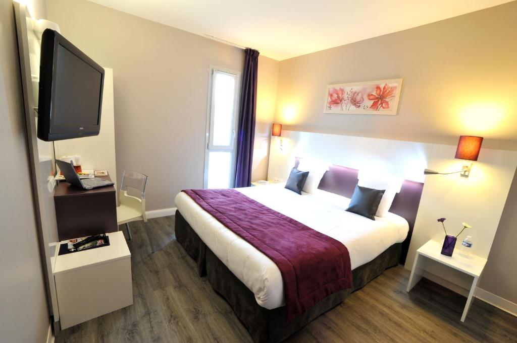 a hotel room with a bed and a flat screen tv at The Originals City, Hotel Novella Premium, Nantes Est in Carquefou