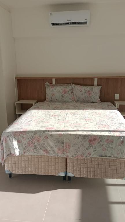 a bedroom with a large bed with a floral bedspread at Studio 810 in Marília