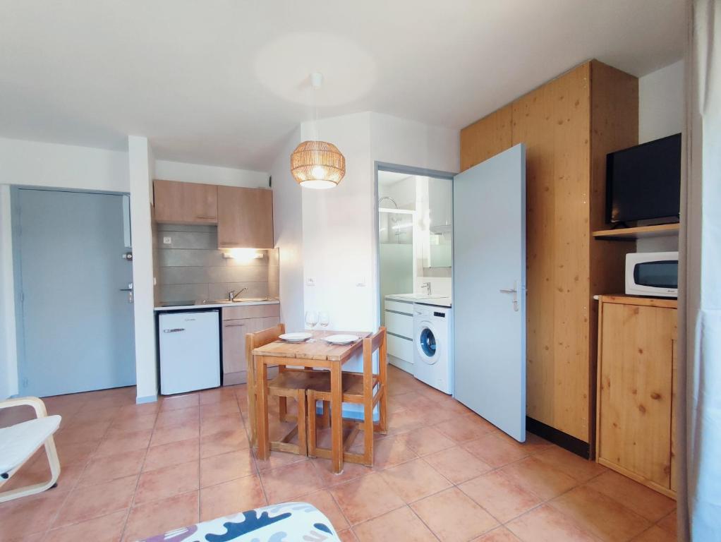 une cuisine avec une petite table et une cuisine avec un four micro-ondes dans l'établissement Le studio des Garrigues - Climatisé, à Gréoux-les-Bains