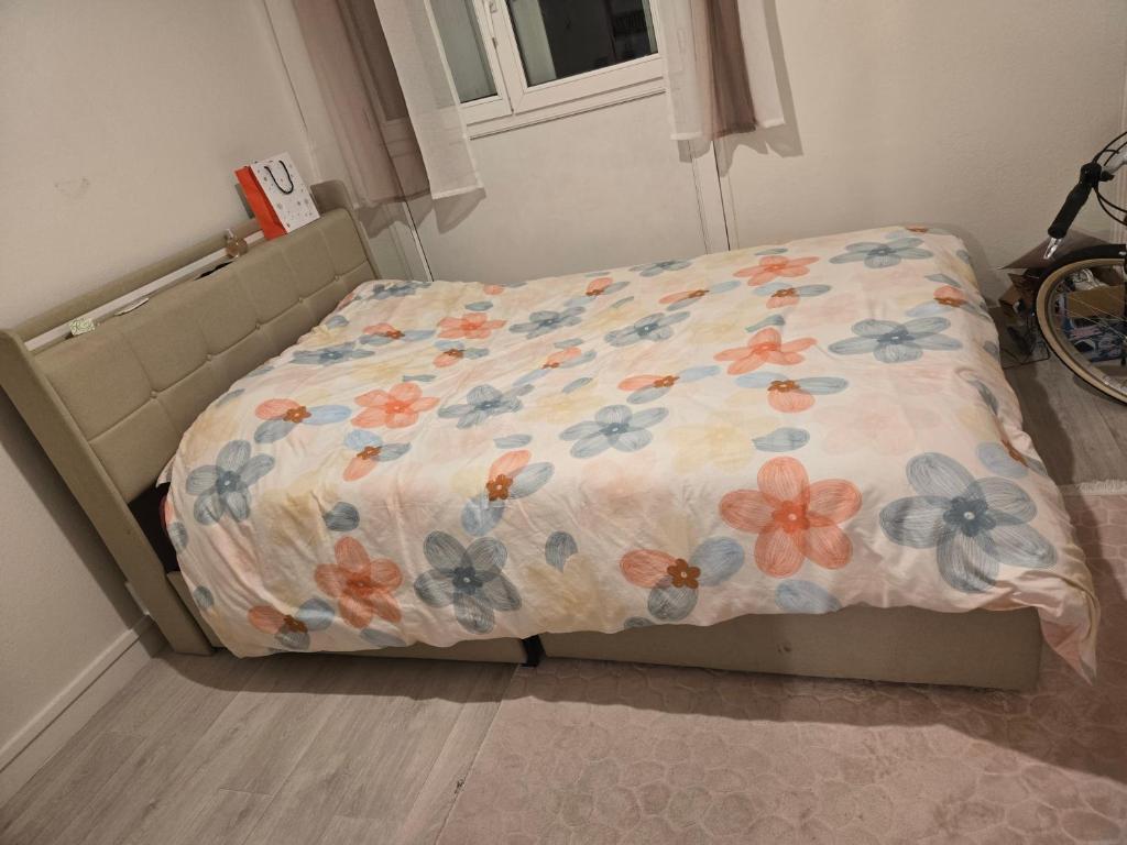 - un lit avec une couette à fleurs dans une chambre dans l'établissement Chika, à Tours