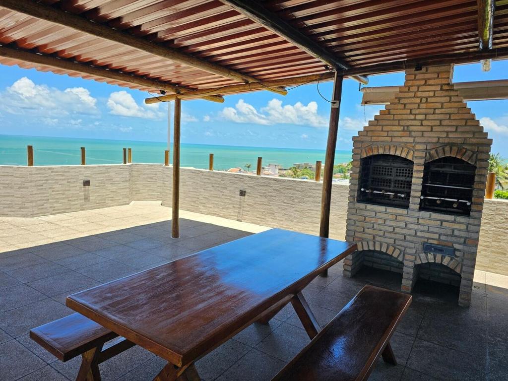 a wooden table on a patio with a brick oven at Apto 201 l 300m da Praia l Wi-Fi, AC - Pirangi do Norte in Parnamirim