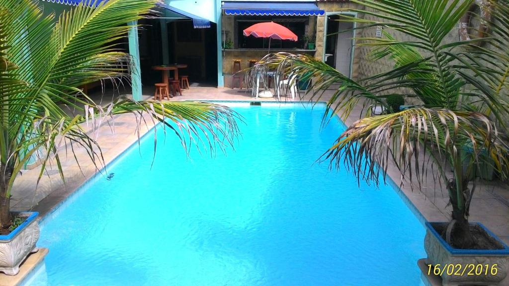 uma grande piscina azul com palmeiras ao lado de um edifício em Suítes Casa Verde em Arraial do Cabo