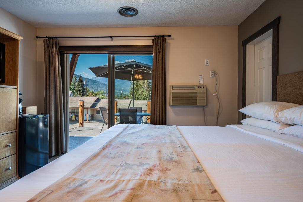 a bedroom with a bed and a patio with an umbrella at Swiss Chalet Motel in Revelstoke