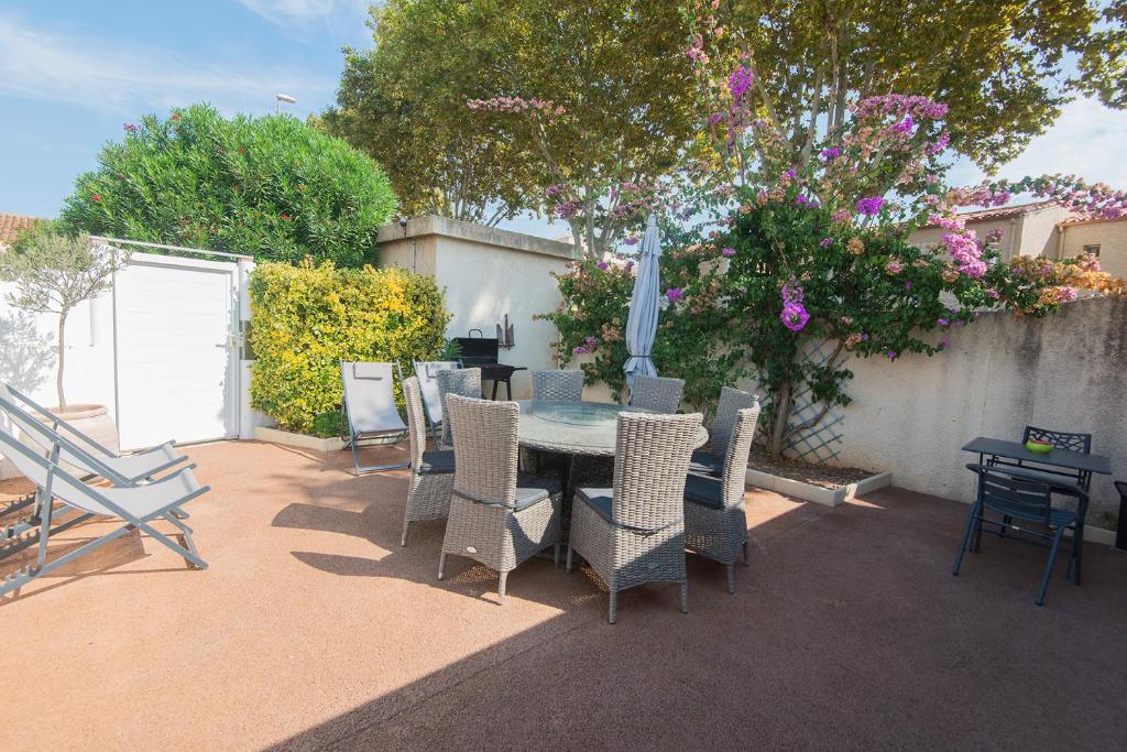 une terrasse avec une table, des chaises et un parasol dans l'établissement maison 6-8 personnes, 3 étoiles, au Cap d'Agde