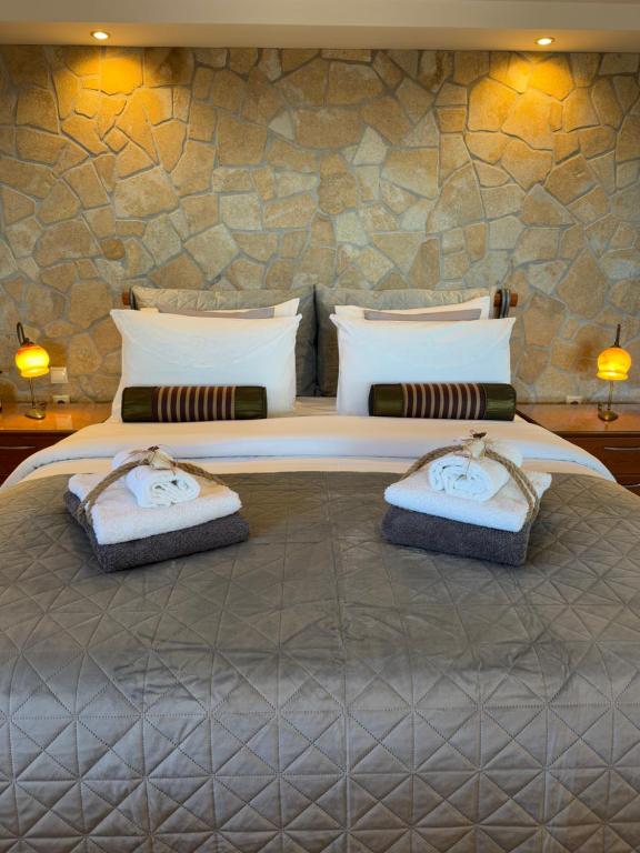 una camera da letto con un letto grande con asciugamani sopra di Wait 'N Sea, Jacuzzi, Luxury Stone House a Epanomi