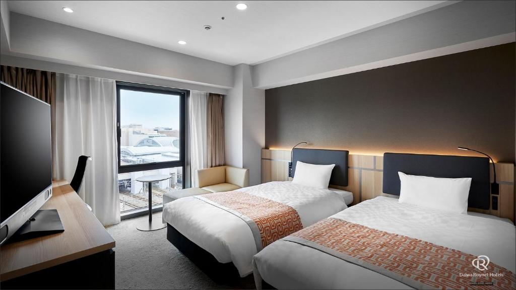 a hotel room with two beds and a window at Daiwa Roynet Hotel Kanazawa Eki Nishiguchi in Kanazawa