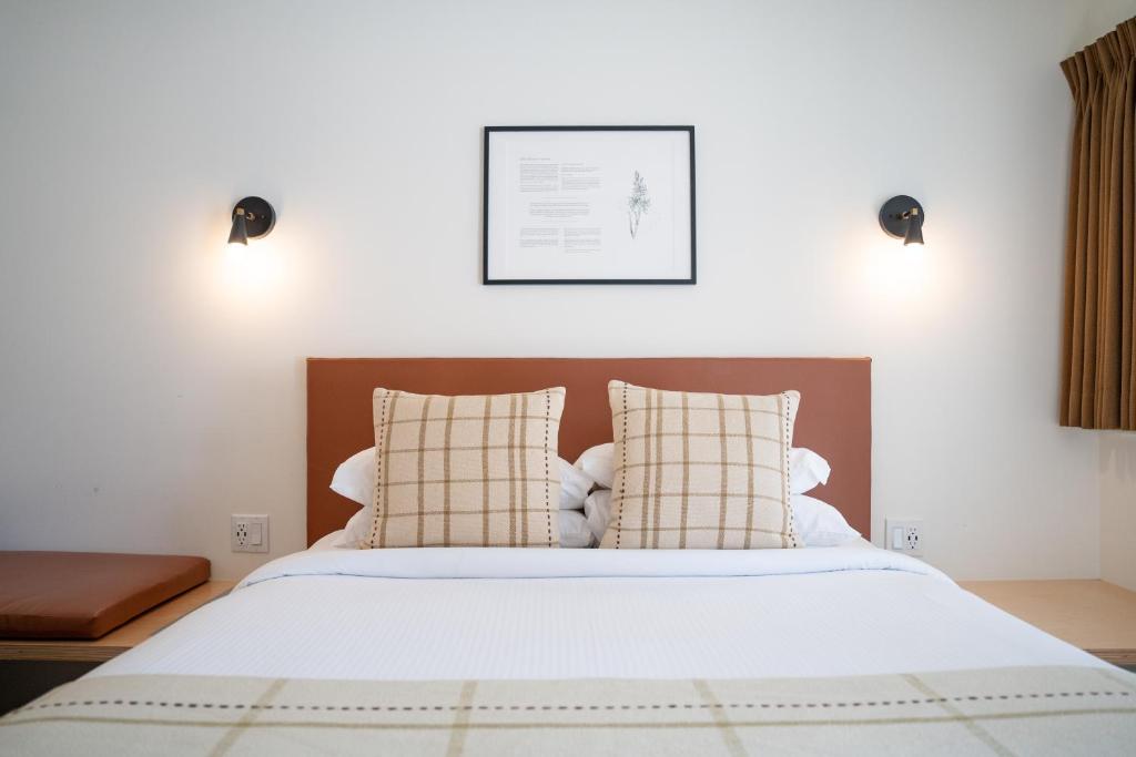 a bedroom with a white bed with two pillows at Swiss Chalet Motel in Revelstoke